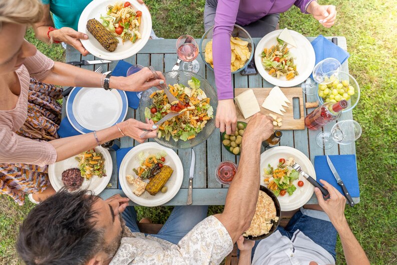 Table familiale en bois avec plats maison lors d'un déjeuner ensoleillé