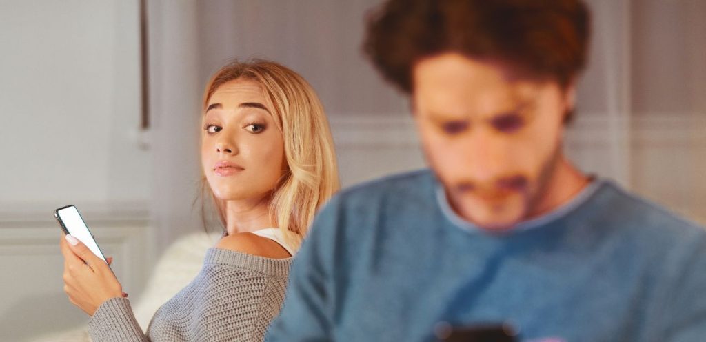 Couple assis dos à dos sur un canapé, regard perdu dans le vide