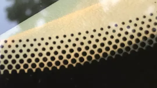 Détail des points noirs sur un pare-brise de voiture