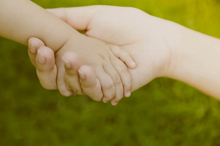 Main d'adulte tenant une main de bébé