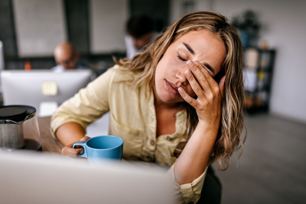 Femme épuisée se frottant les yeux au travail