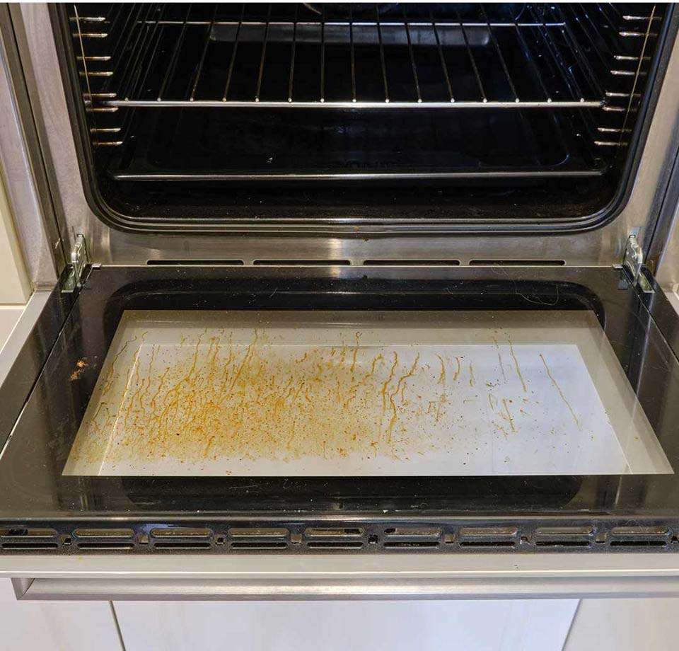 Gros plan sur des saletés incrustées entre les vitres d'une porte de four