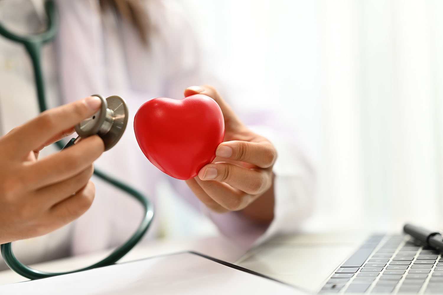Médecin tenant un stéthoscope et un cœur rouge. Concept de consultation médicale cardiaque.