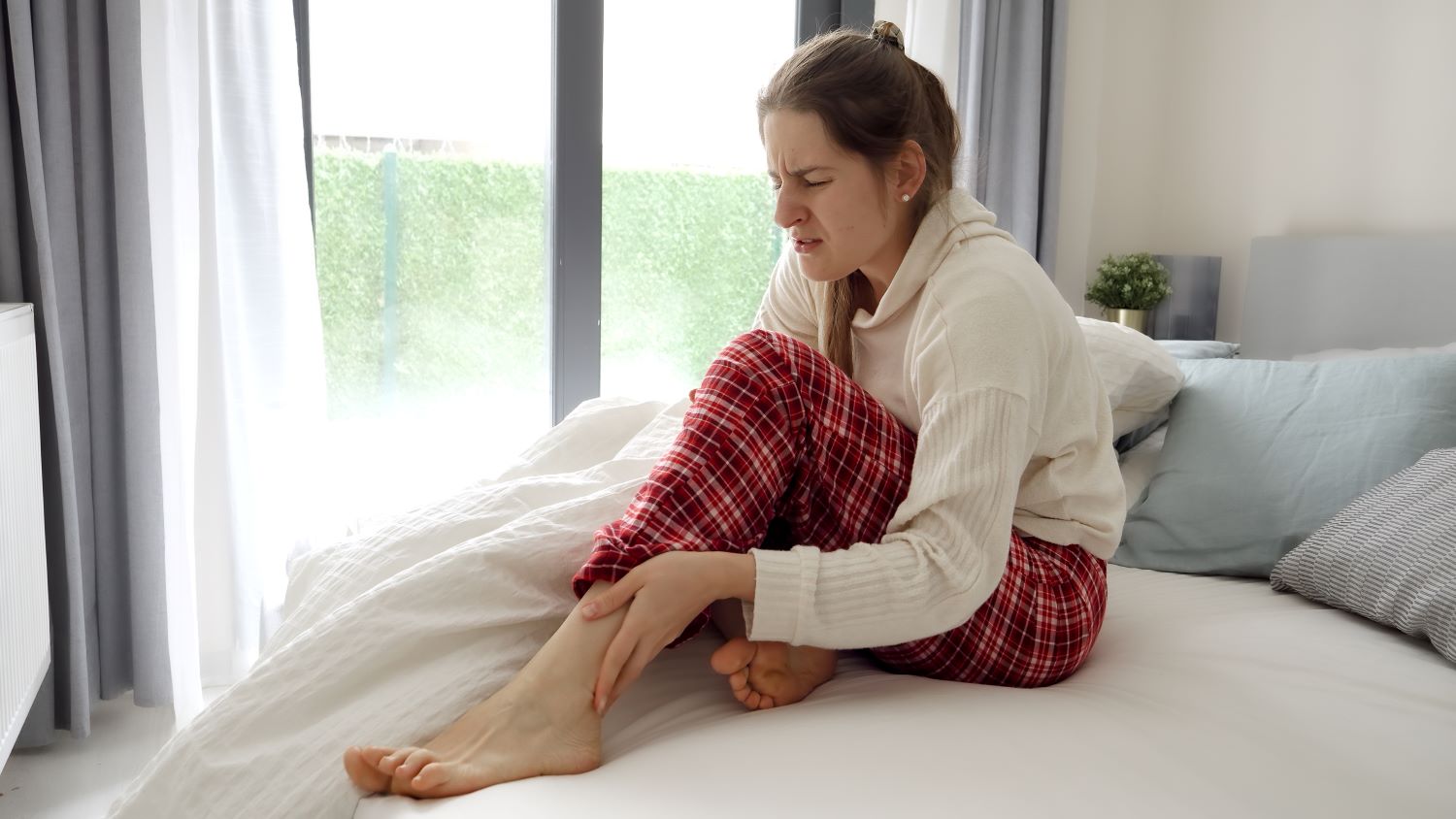 Femme ressentant une crampe à la jambe pendant la nuit