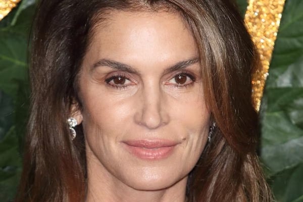 Cindy Crawford souriante, arborant des cheveux légèrement argentés avec naturel et confiance