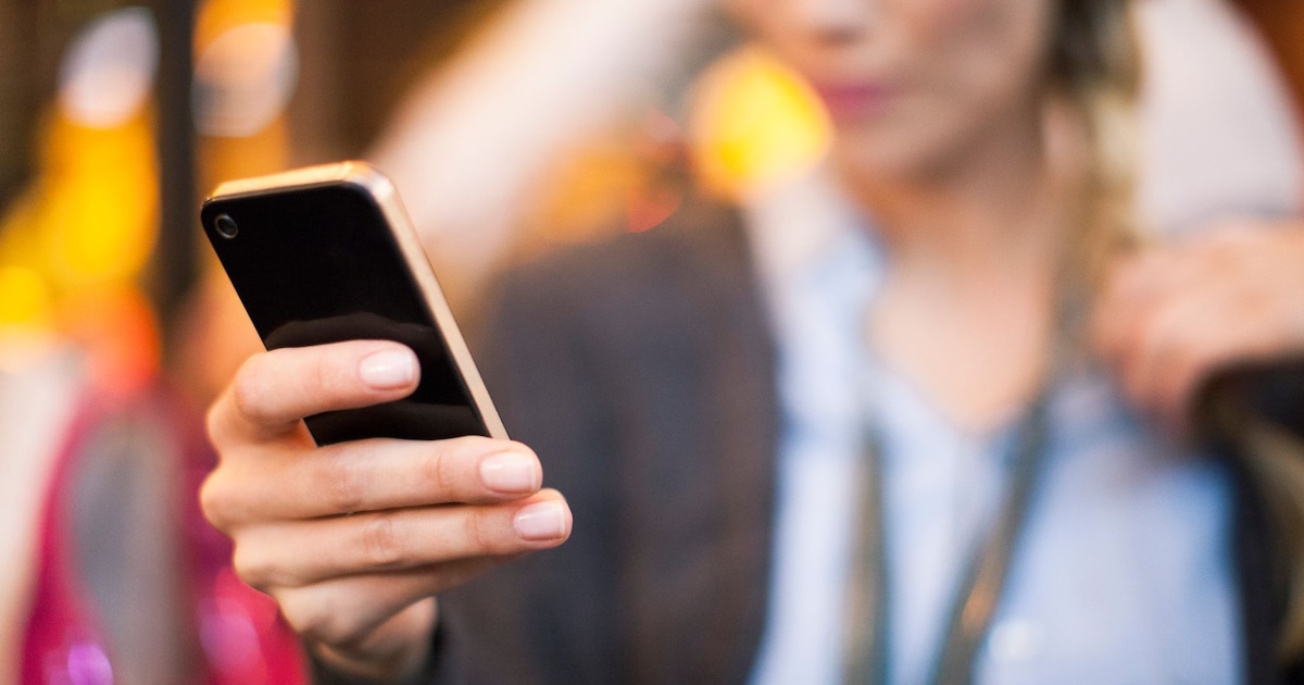 Femme regardant un téléphone portable, expression déterminée
