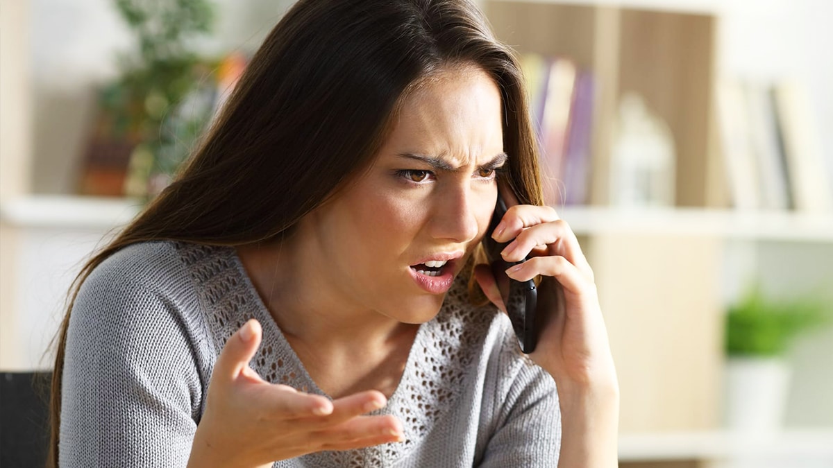 Une femme sourit au téléphone en ayant l'air sereine