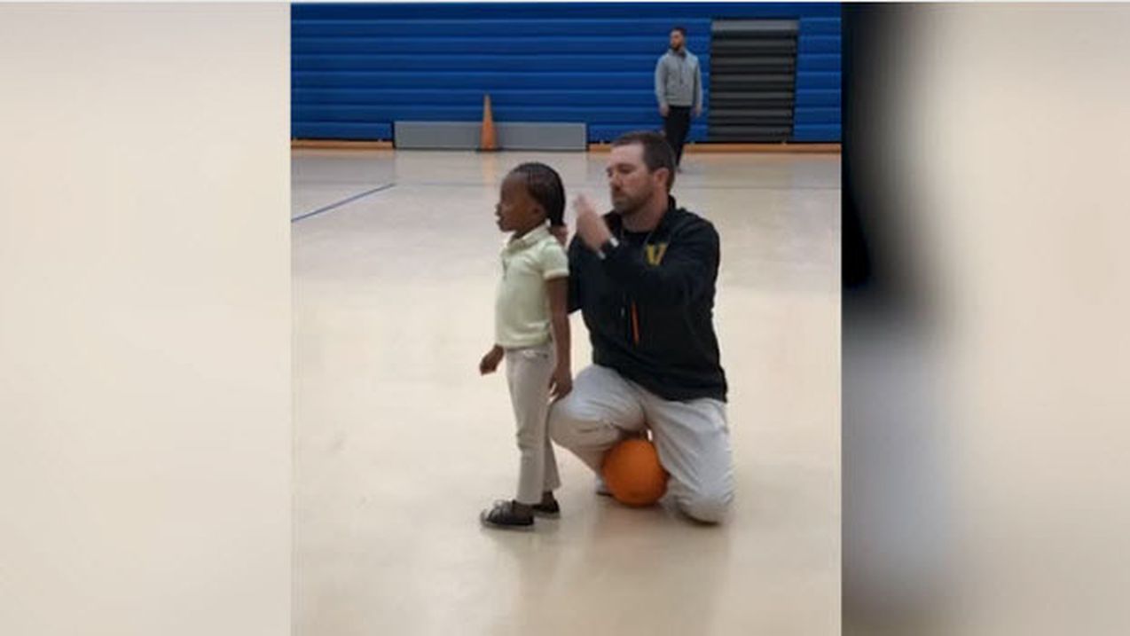 L'entraîneur attache les cheveux d'une petite joueuse de basket