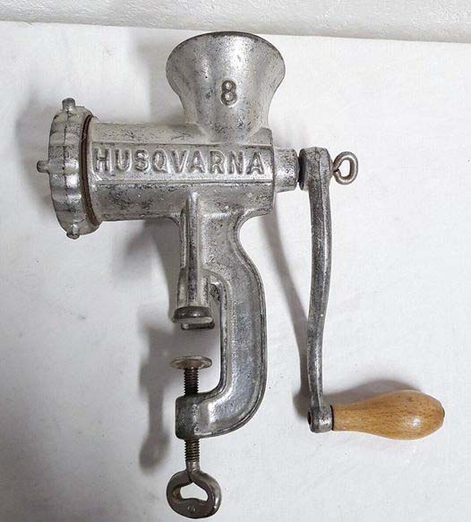 Photo d'un hachoir à viande ancien en métal posé sur une table