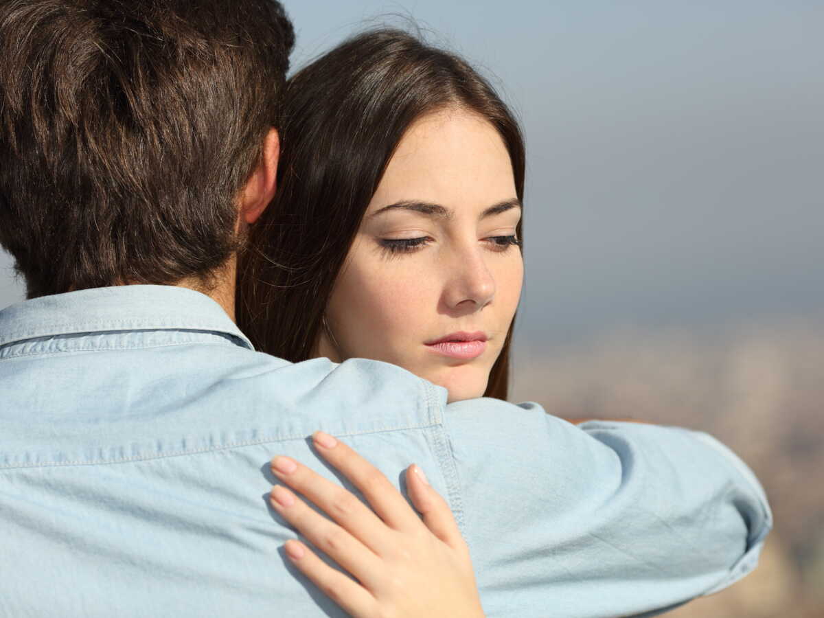 Une femme regardant pensivement par la fenêtre, évoquant la suspicion et la réflexion.