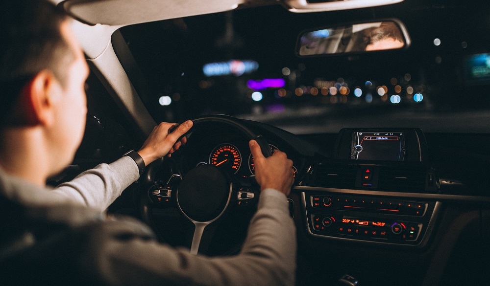Jeune femme conduisant prudemment de nuit, regard concentré sur la route
