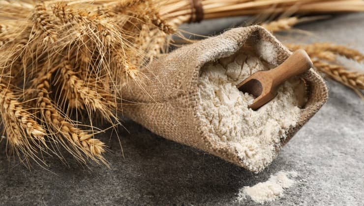 Sac de farine et cuillère en bois sur un plan de travail